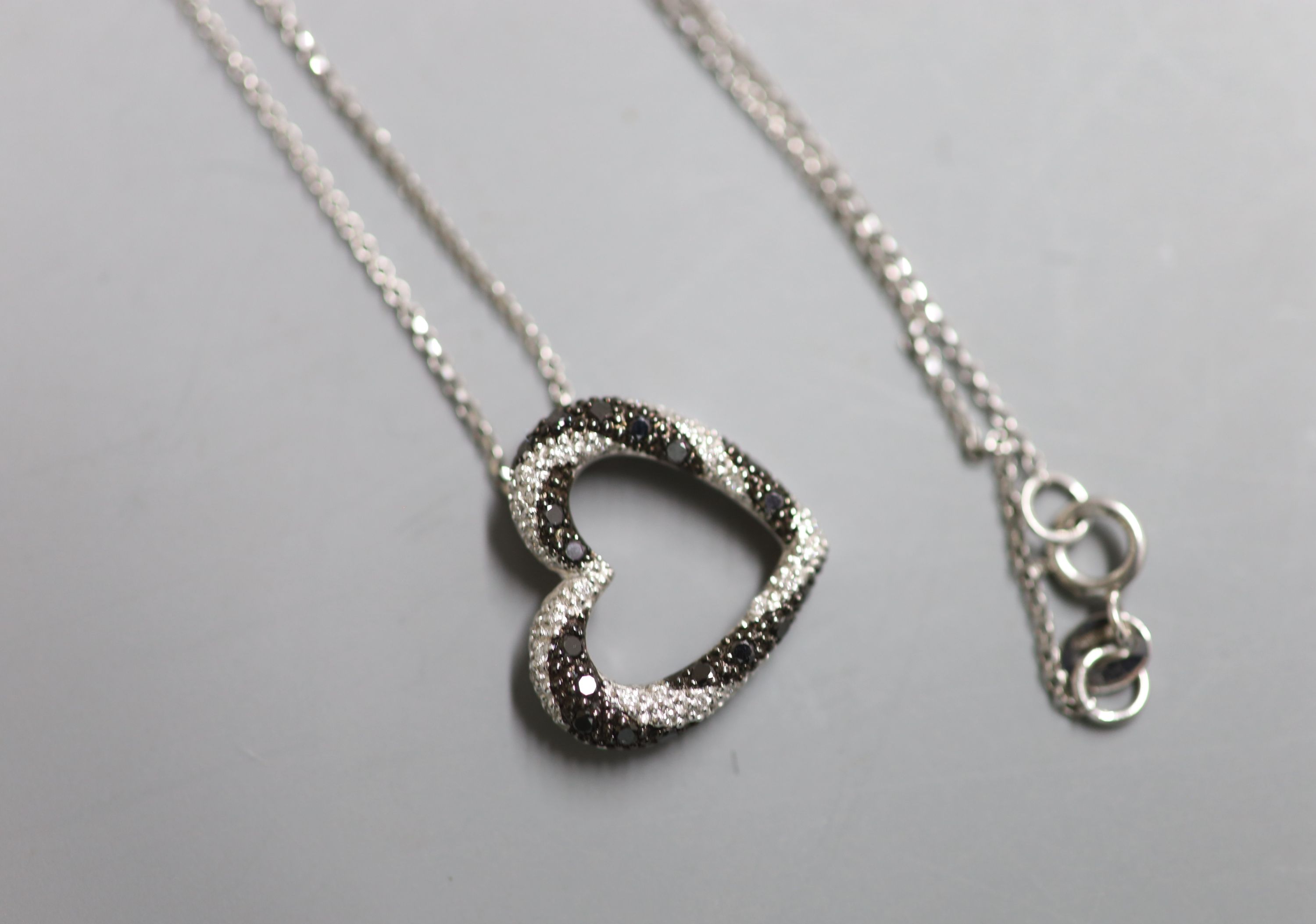 A modern 18ct gold and two colour diamond chip set openwork heart pendant, 16mm, on an 18ct gold fine link chain